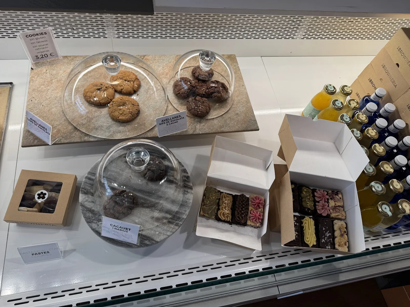 Taulell amb cookies sota campanes de vidre i capses