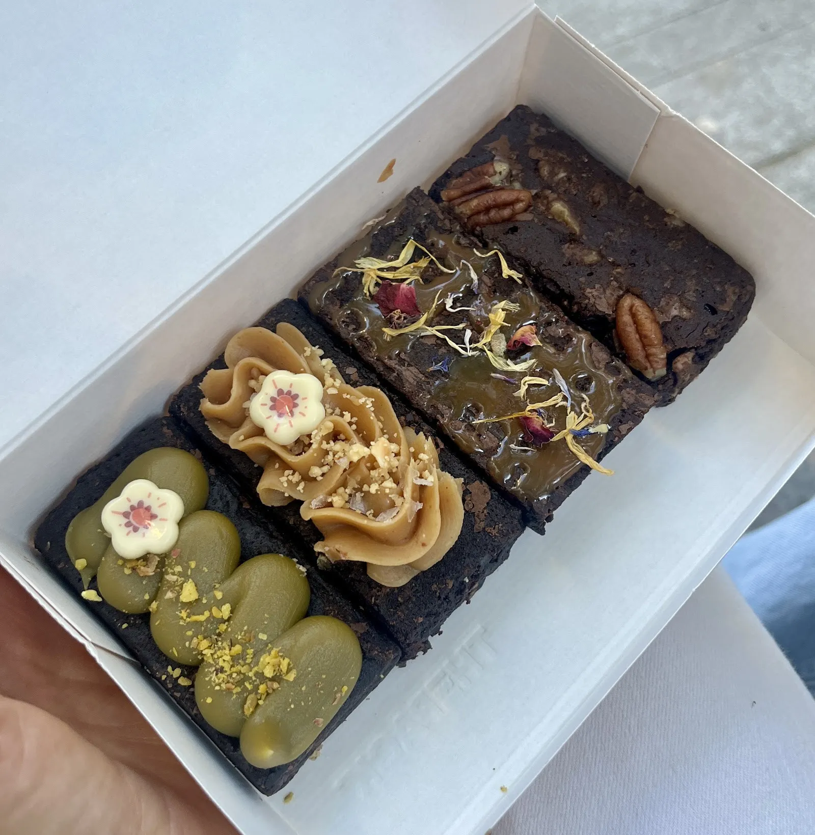 Capsa de 4 brownies decorats, entre ells un de pistatxo
